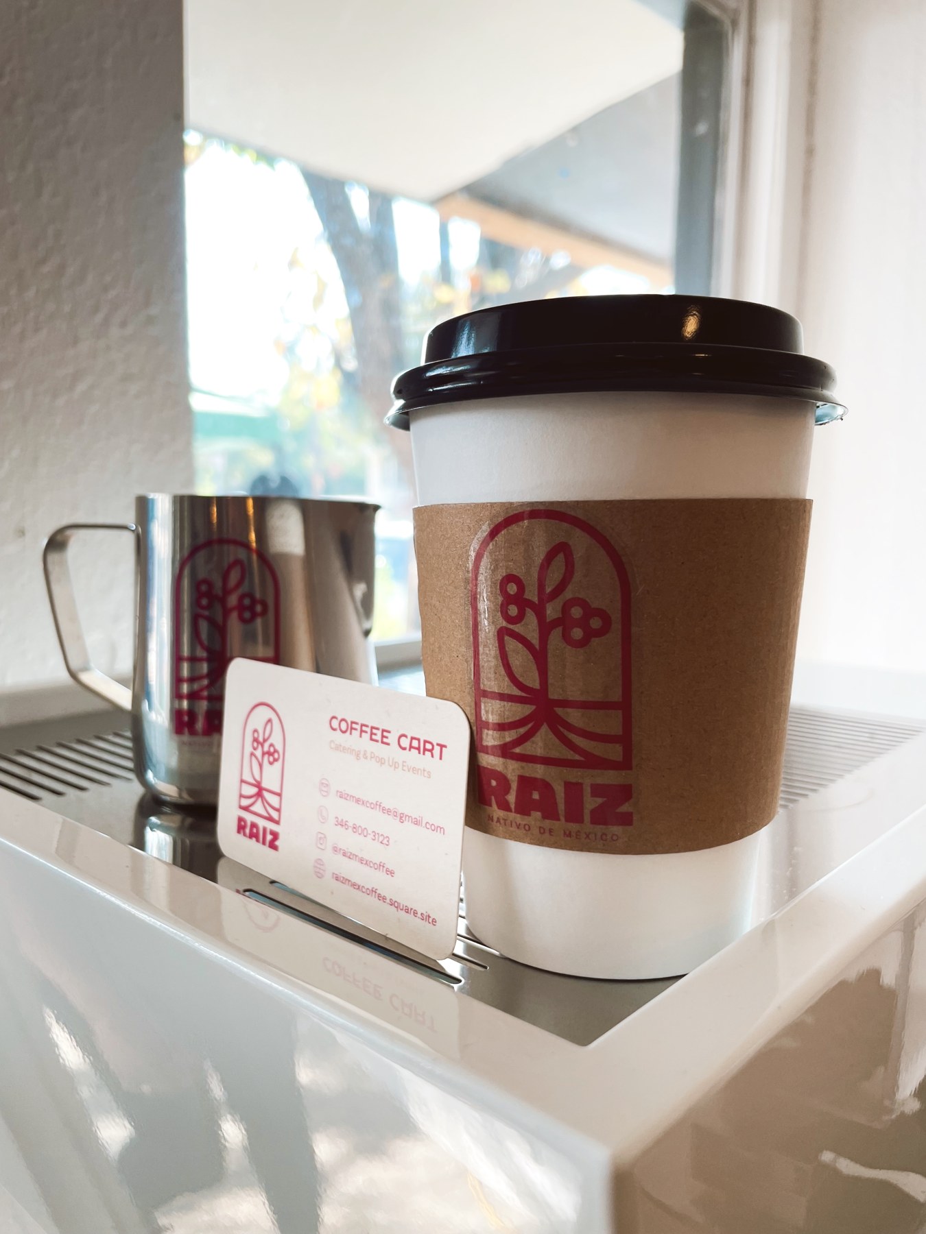 Raíz takeaway coffee cup beside the espresso machine